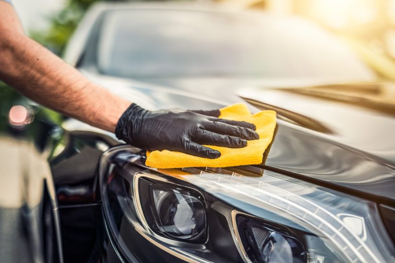 Car detailing - the man holds the microfiber in hand and polishes the car. Selective focus.